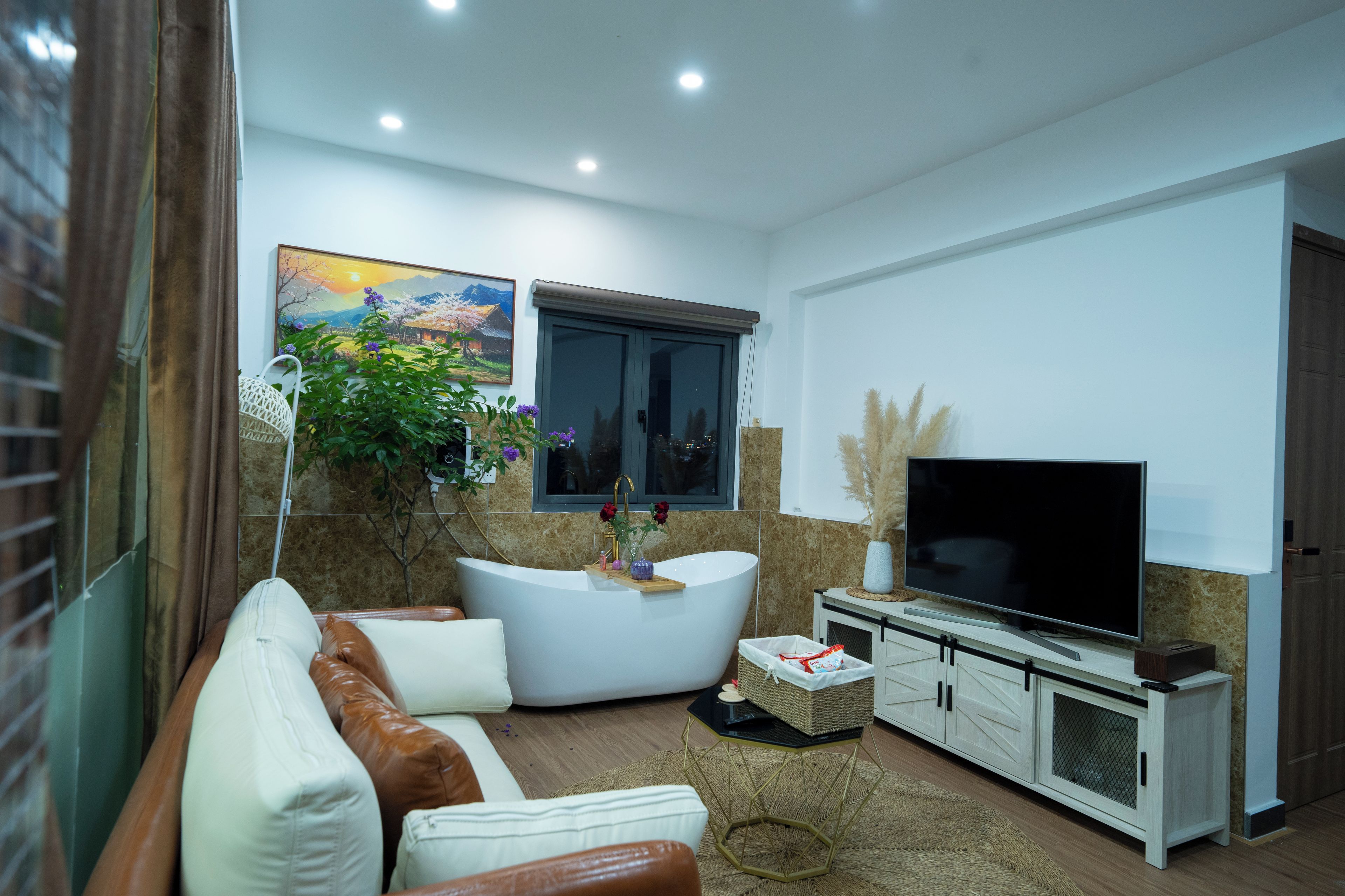 Ein modernes Wohnzimmer mit einem weißen Sofa, einem gewölbten weißen Couchtisch, einem Flachbildfernseher auf einem Holzständer und einem Gemälde an der Wand.