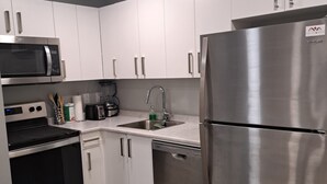 Una cocina moderna con electrodomésticos de acero inoxidable, armarios blancos y encimera de mármol.