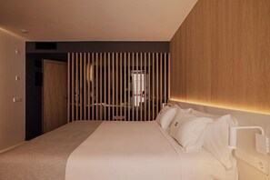 A modern hotel room with a large bed, a wooden headboard, and a vertical wooden slat partition. - Apartamentos Los Robles (Ibiza Town)