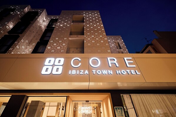 The exterior of the Core Ibiza Town Hotel with illuminated signage and a modern architectural design. - Apartamentos Los Robles (Ibiza Town)