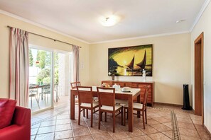 Ein Essbereich mit Tisch und Stühlen, einem Bild an der Wand und Blick durch die Glastür.