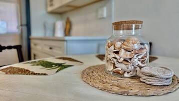 A glass jar filled with seashells on a woven placemat, placed on a table with a patterned placemat.