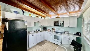 A compact kitchen with white cabinets, a black refrigerator, a microwave, and a stove.