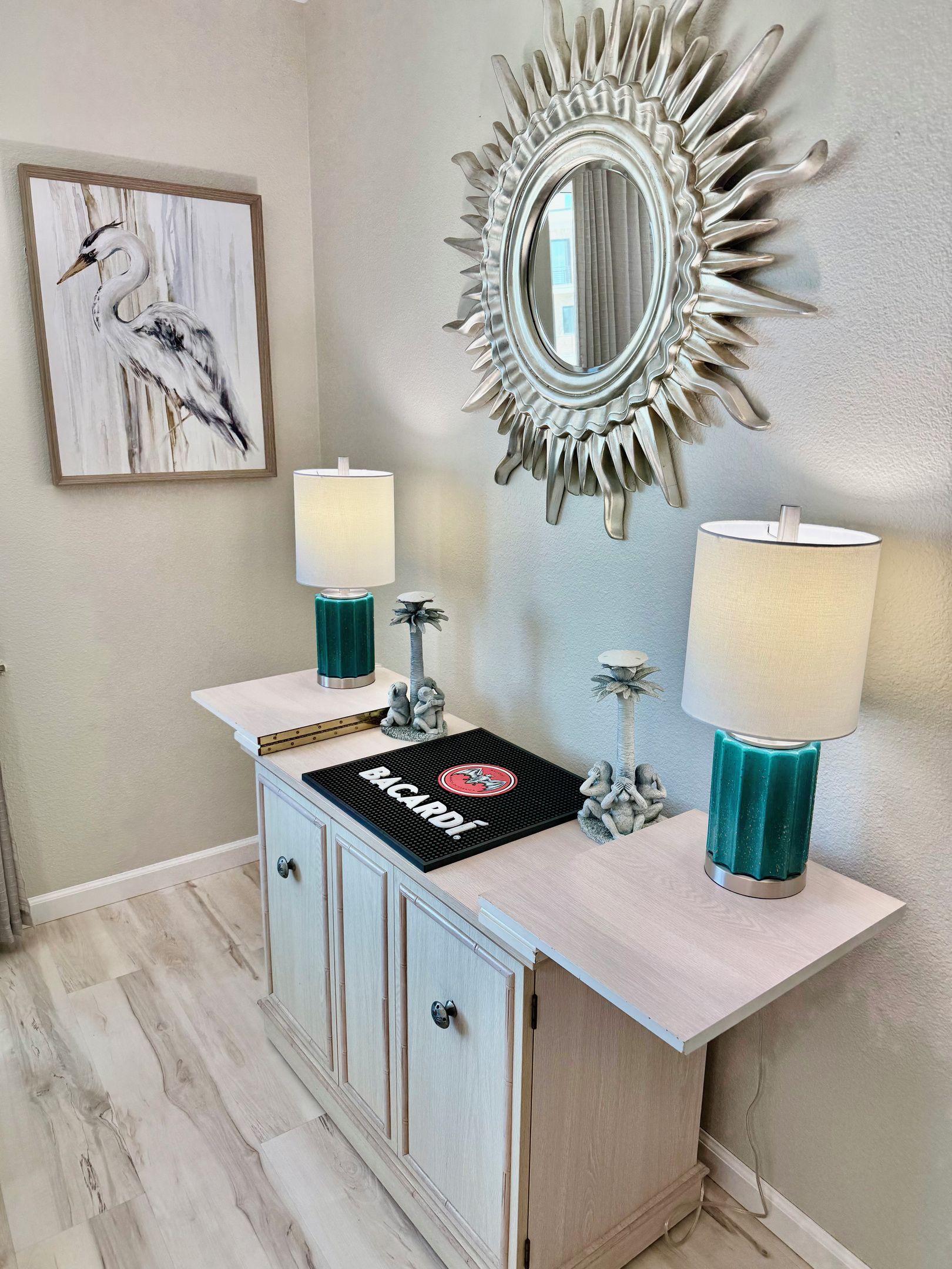 A bathroom with a vanity, two wall-mounted lamps, a decorative mirror, and a framed artwork.