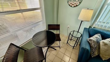 A living room with a blue sofa, a round table, and a chair. There is a wall decoration with a beach theme.