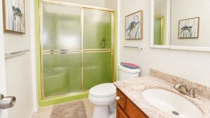 Ein Badezimmer mit Dusche, Toilette, Waschbecken und Spiegel.