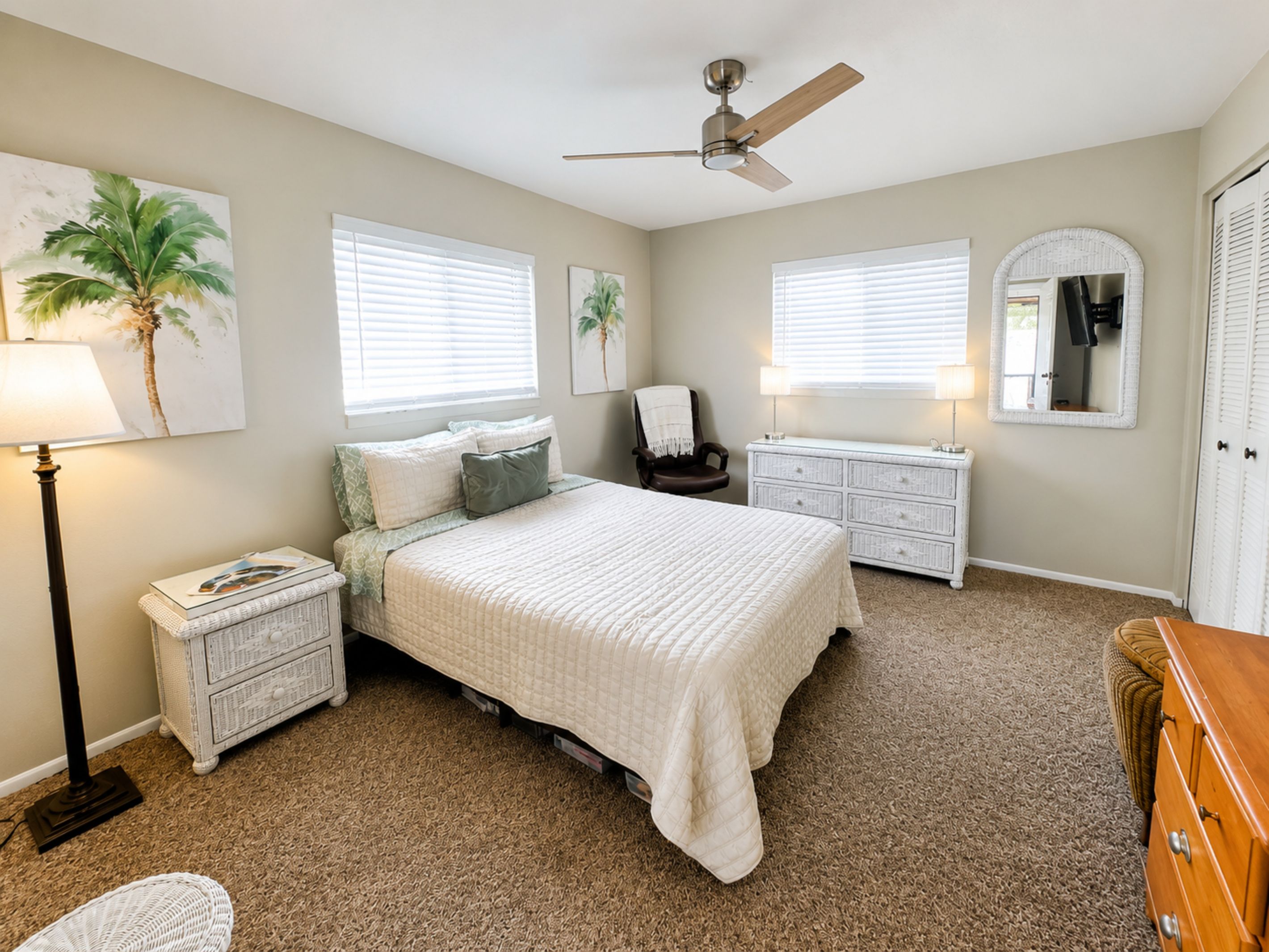 A bedroom with a bed, nightstands, a dresser, a chair, a ceiling fan, and two windows with blinds.