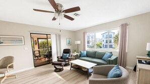 Ein geräumiges Wohnzimmer mit Deckenventilator, einer Couch, einem Sessel und einem Esstisch.