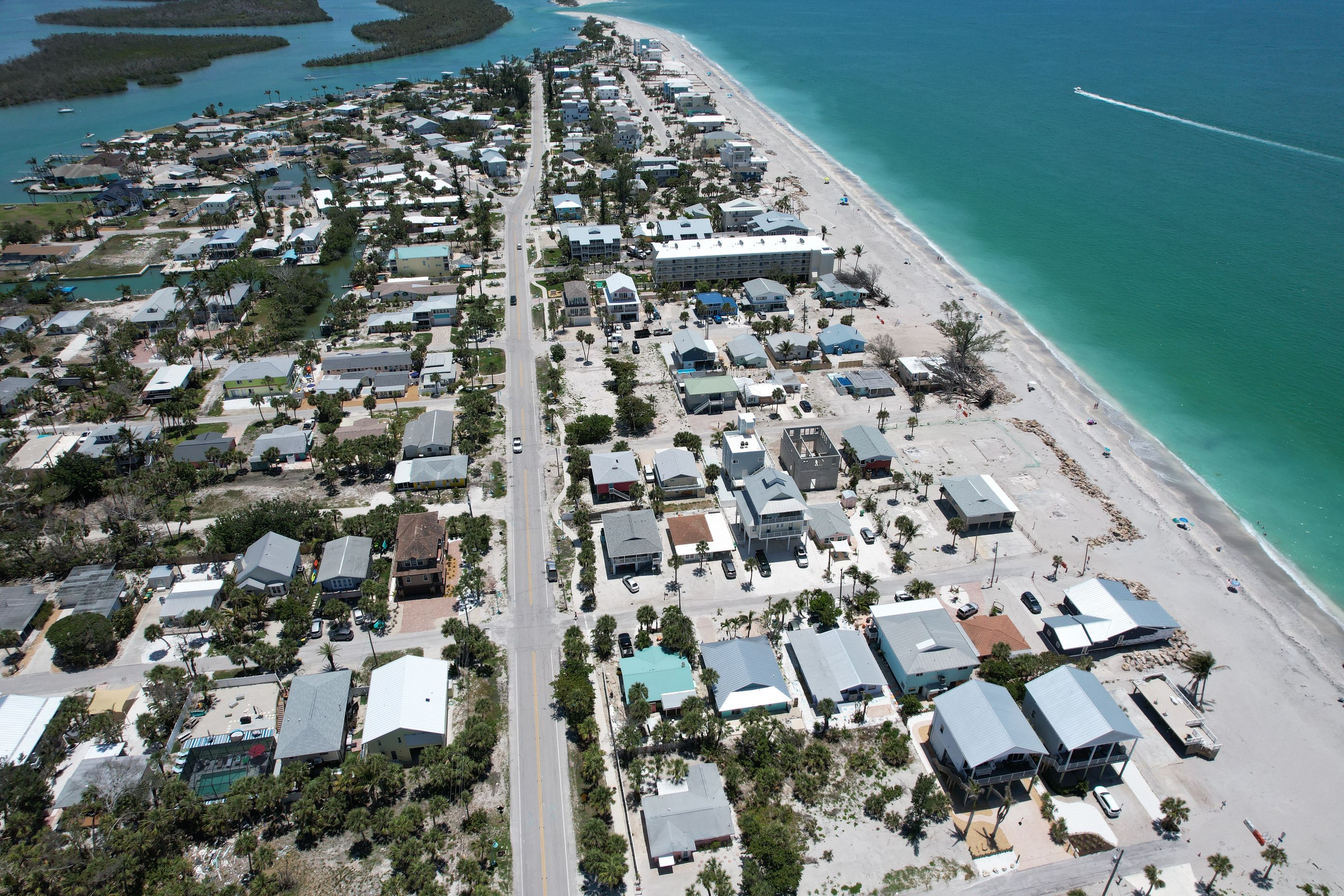 Vista aérea de uma área residencial costeira, com casas, uma avenida principal e uma praia.