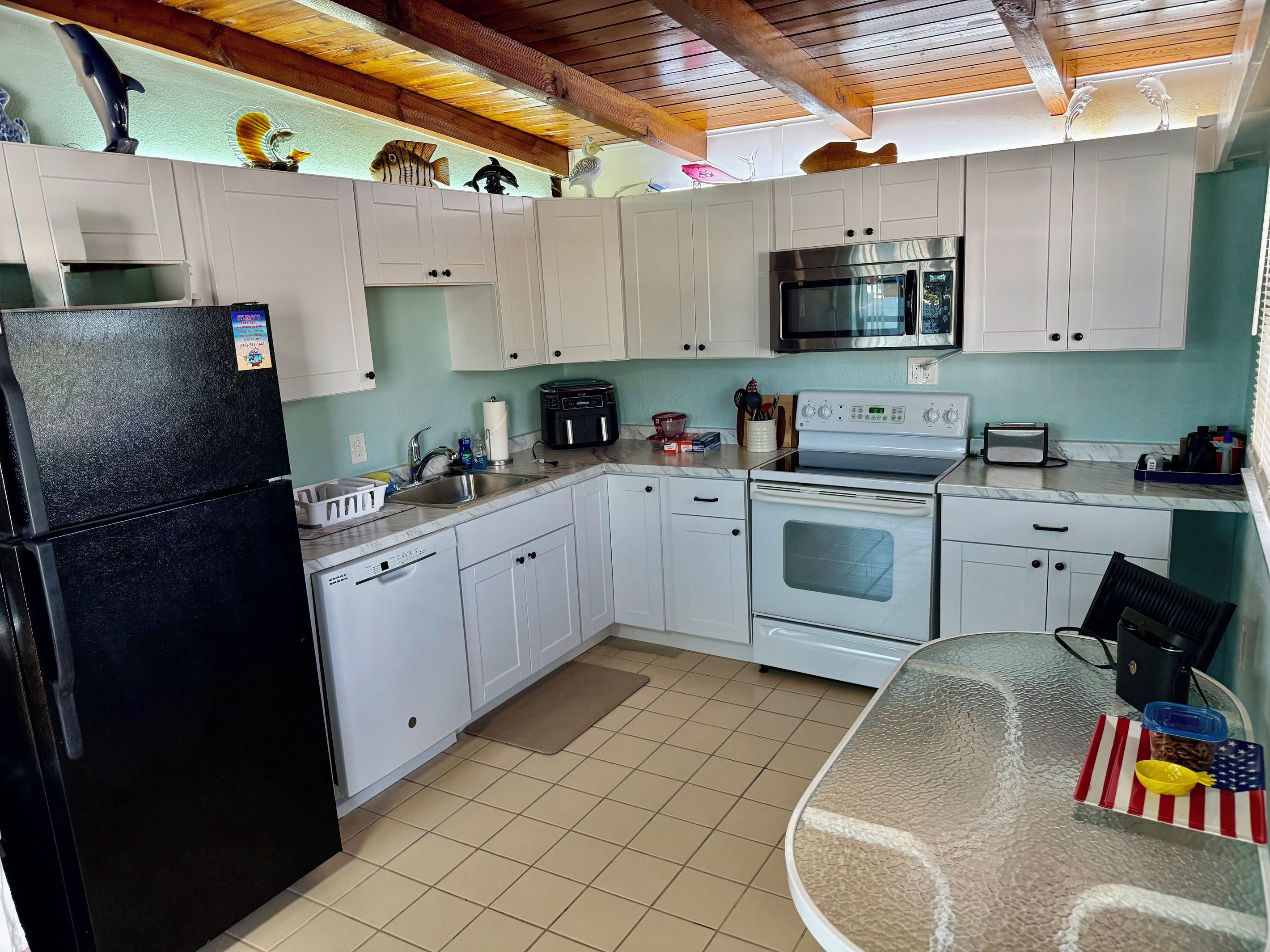 A kitchen with white cabinets, a black refrigerator, a microwave, and a stove.
