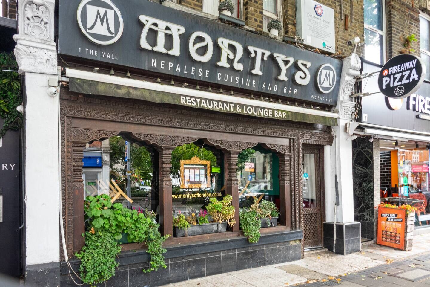 A restaurant with a sign reading 'MONTYS NEPALSE CUISINE AND BAR' and a 'FIREWAY PIZZA' sign nearby.