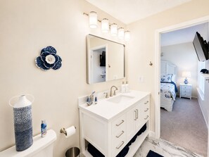 A bathroom with a white vanity, a large mirror, and a blue decorative item on the wall. - Coastal Condo w/ Pool, Bay Dock & Beach Vibes (Englewood)