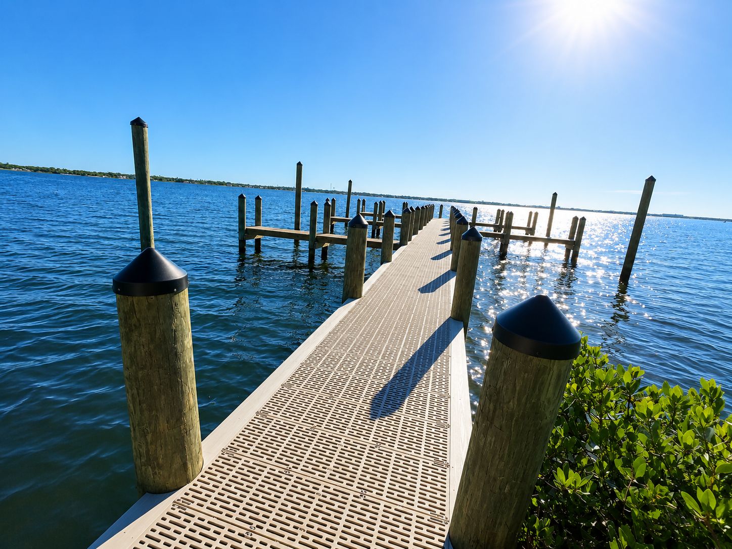 A wooden pier extending into calm water with a clear sky above.