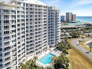Ein Hochhaus-Hotel mit mehreren Etagen, einem Schwimmbad und Blick auf den Strand.