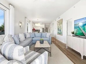 Ein modernes Wohnzimmer mit einer Eckcouch, einem Couchtisch und einem Fernseher auf einem Lowboard.
