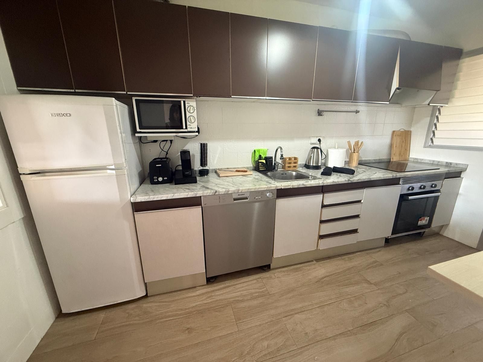 Eine moderne Küche mit Kühlschrank, Mikrowelle, Geschirrspüler, Herd und einer Marmorarbeitsplatte.