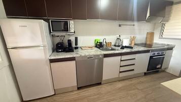 Eine moderne Küche mit Kühlschrank, Mikrowelle, Geschirrspüler, Herd und einer Marmorarbeitsplatte.