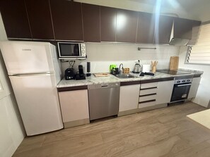 Une cuisine moderne équipée d’un réfrigérateur, d’un four à micro-ondes, d’un lave-vaisselle, d’une cuisinière et d’un plan de travail en marbre.