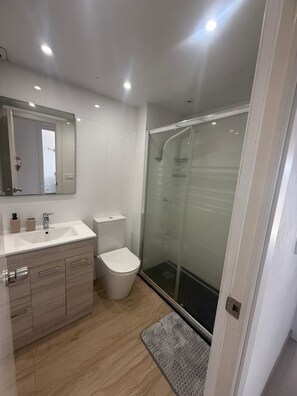 A modern bathroom with a glass shower enclosure, a white sink, and a toilet. - Salou at Your Feet | Beach, Views, and Relaxation (Salou)