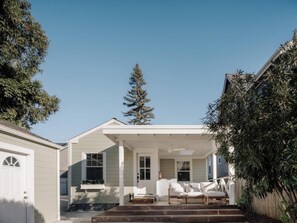A house with a covered porch, a front door, and a small seating area with cushions. - Designer Napa Cottage - Walk to Downtown + Chef’s Kitchen (Napa)