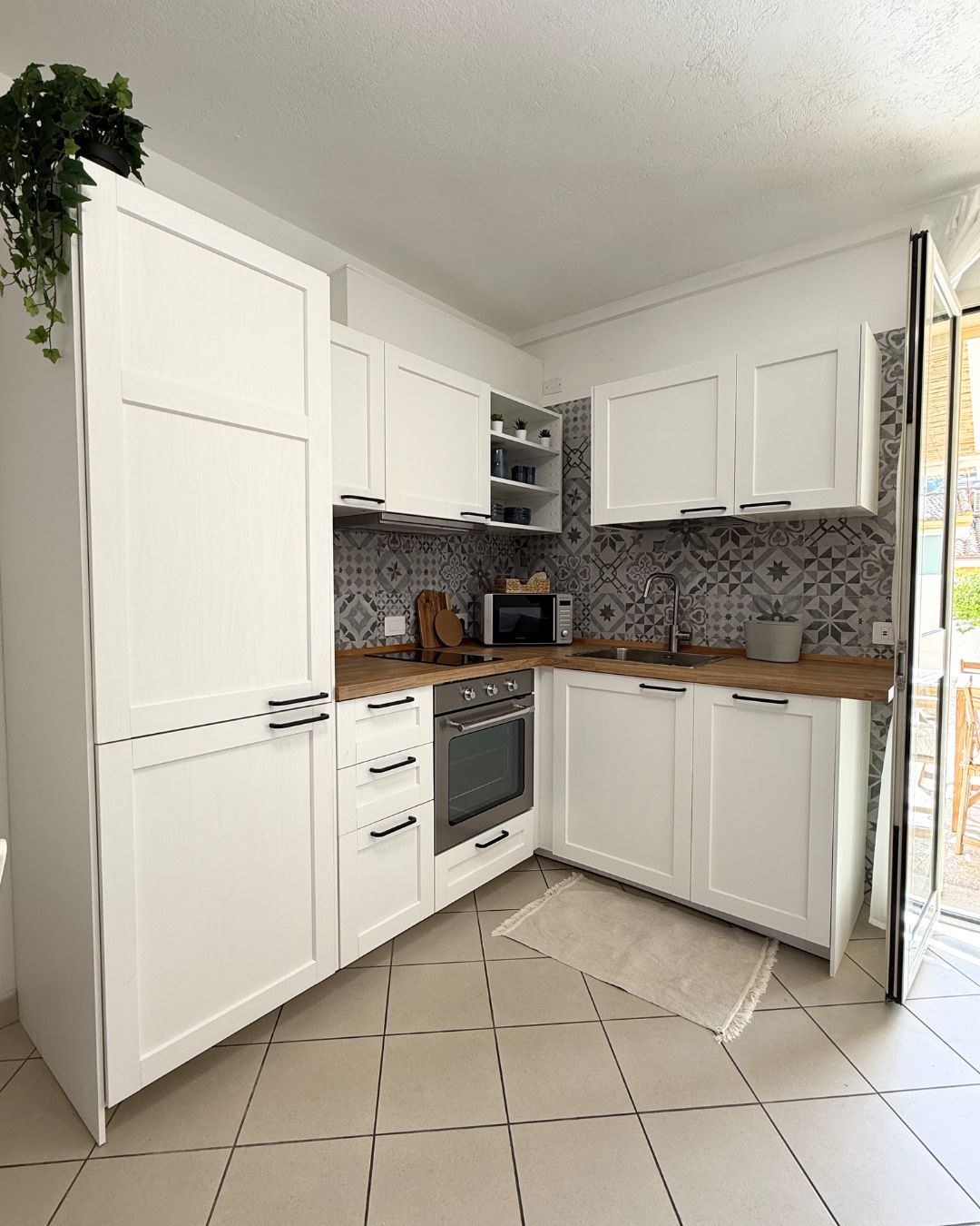 Een kleine keuken met witte kastjes, een magnetron, een oven en een klein aanrecht.