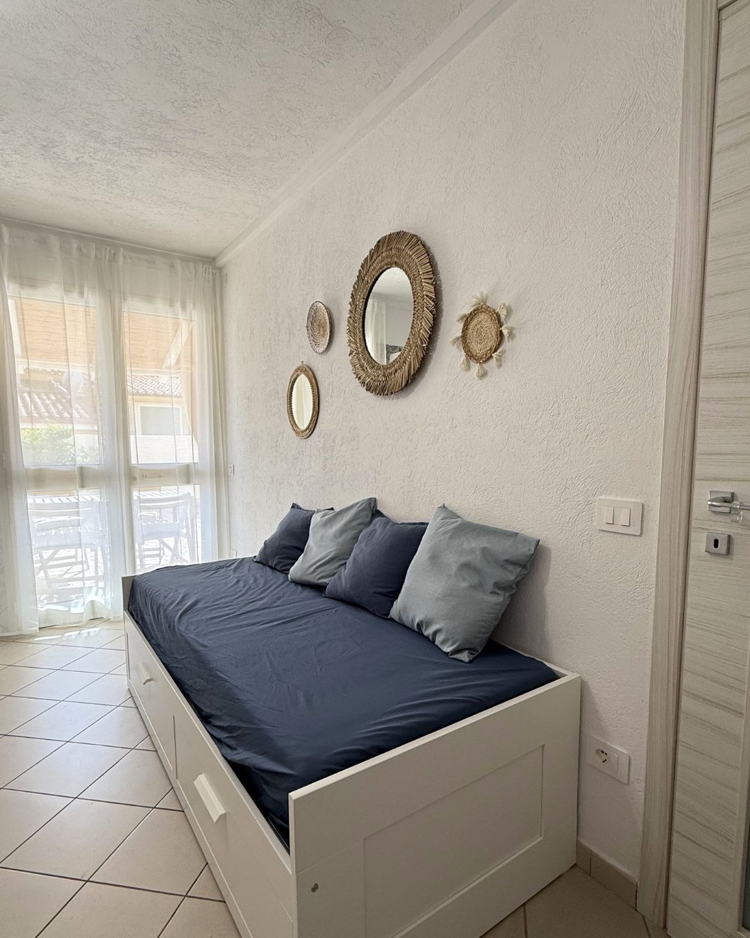 Ein Schlafzimmer mit einem Bett, einem großen Spiegel und einem Fenster mit Vorhängen.