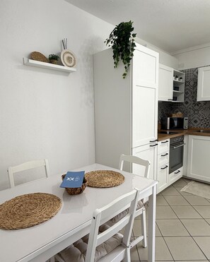 A modern kitchen with white cabinets, a microwave, and a hanging plant. - Comfortable downtown apartment with a terrace (Villasimius)