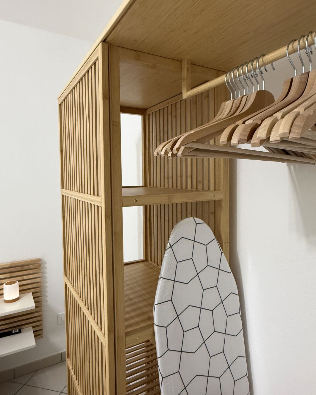 A room with a wooden partition, a clothing rack, and a white tiled wall.