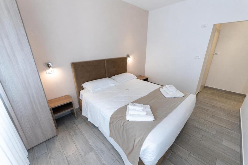 Una habitación de hotel con cama, mesitas de noche y una puerta.