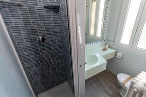 Un baño con ducha, lavamanos, inodoro y ventana.