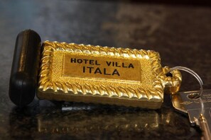 A gold keychain with 'HOTEL VILLA ITALA' engraved on it. - Hotel Villa Itala (Rimini)