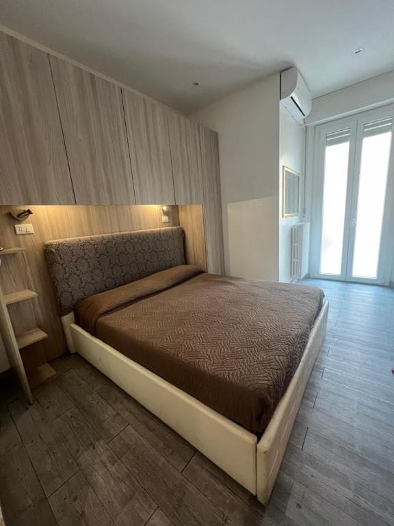 Un dormitorio con cama, armario empotrado y ventana.