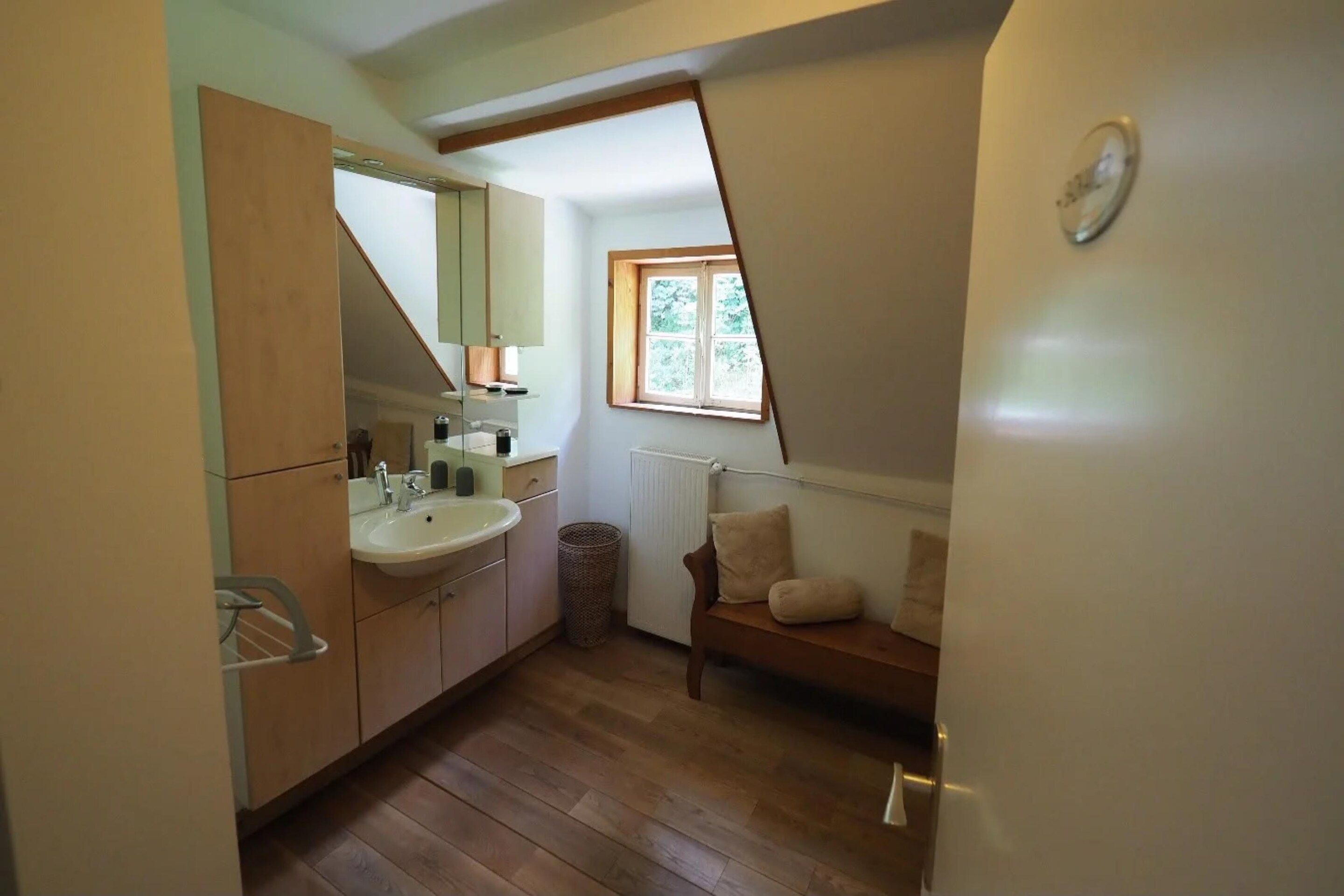 Ein kleines Badezimmer mit Waschbecken, Spiegel und Fenster.