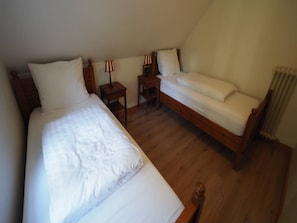 Ein Schlafzimmer mit zwei Betten, einem Nachttisch, einem Sessel und einer Lampe.