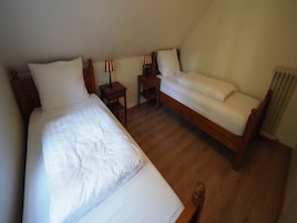 Un dormitorio con dos camas, una mesita de noche, una silla y una lámpara.