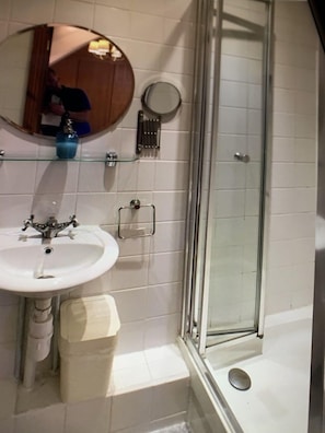 A bathroom with a white sink, a round mirror, a glass shower enclosure, and a towel rack. - Ty Rosa - Bed & Breakfast (Cardiff)