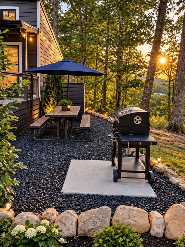 Eine Außenpatio-Terrasse mit Grill, Tisch mit Sonnenschirm und Sitzbank.