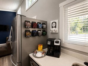 Eine Küche mit Kühlschrank, Kaffeemaschine und einer Wandkaffeestation mit verschiedenen Accessoires.