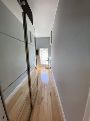 A hallway with wooden flooring, a sliding door, and a window at the end. - Fully Furnished 1BR + Parking | Harbord Village | 5 months: $3800/month Oct–Mar (Toronto)