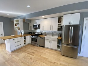 A modern kitchen with white cabinetry, stainless steel appliances, and a wooden countertop. - Fully Furnished 1BR + Parking | Harbord Village | 5 months: $3800/month Oct–Mar (Toronto)