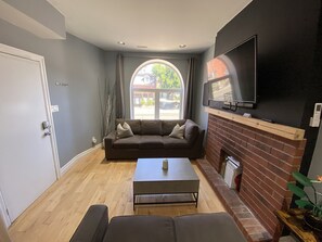 Sala de estar com sofá, mesa de centro, lareira e televisão na parede.