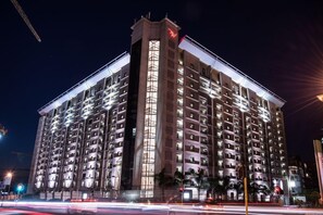 Un hotel de varios pisos con un llamativo logo 'W', con un diseño moderno, balcones y una estructura vertical central.