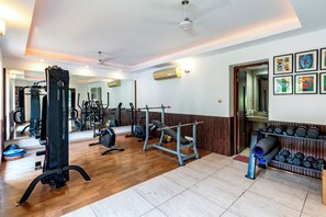 A gym with various exercise equipment, a mirror, and a rack of dumbbells.