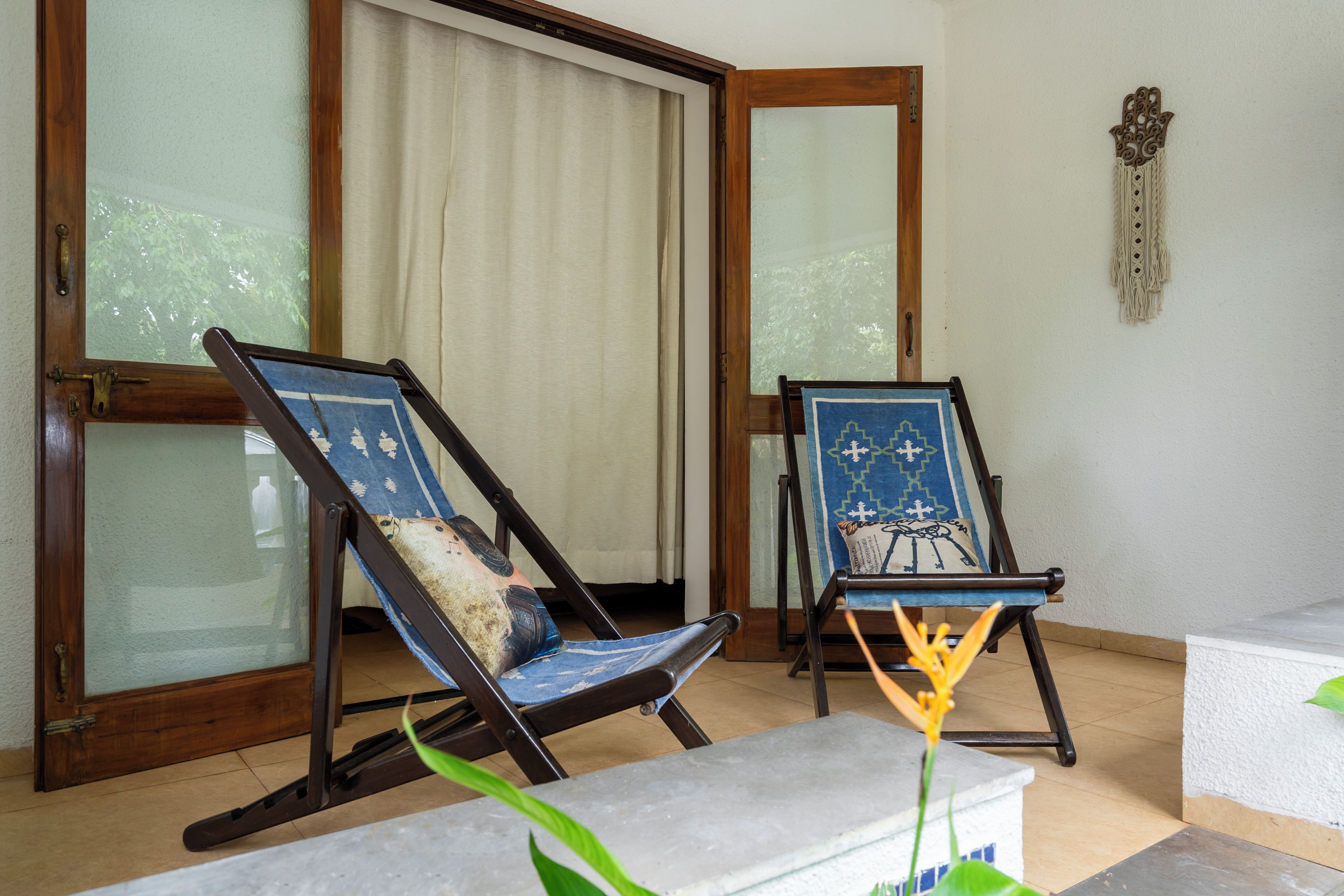 Two lounge chairs with a view of a sliding glass door and a decorative wall piece.