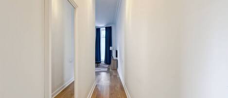 Un couloir étroit avec un plancher en bois et des murs blancs.