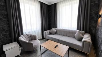 Un salon moderne avec un canapé gris, un fauteuil assorti, une table basse en bois et une petite table d’appoint blanche.