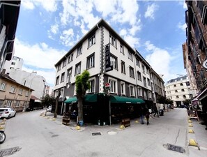 Un edificio de varios pisos con toldo verde y una calle en su fachada.