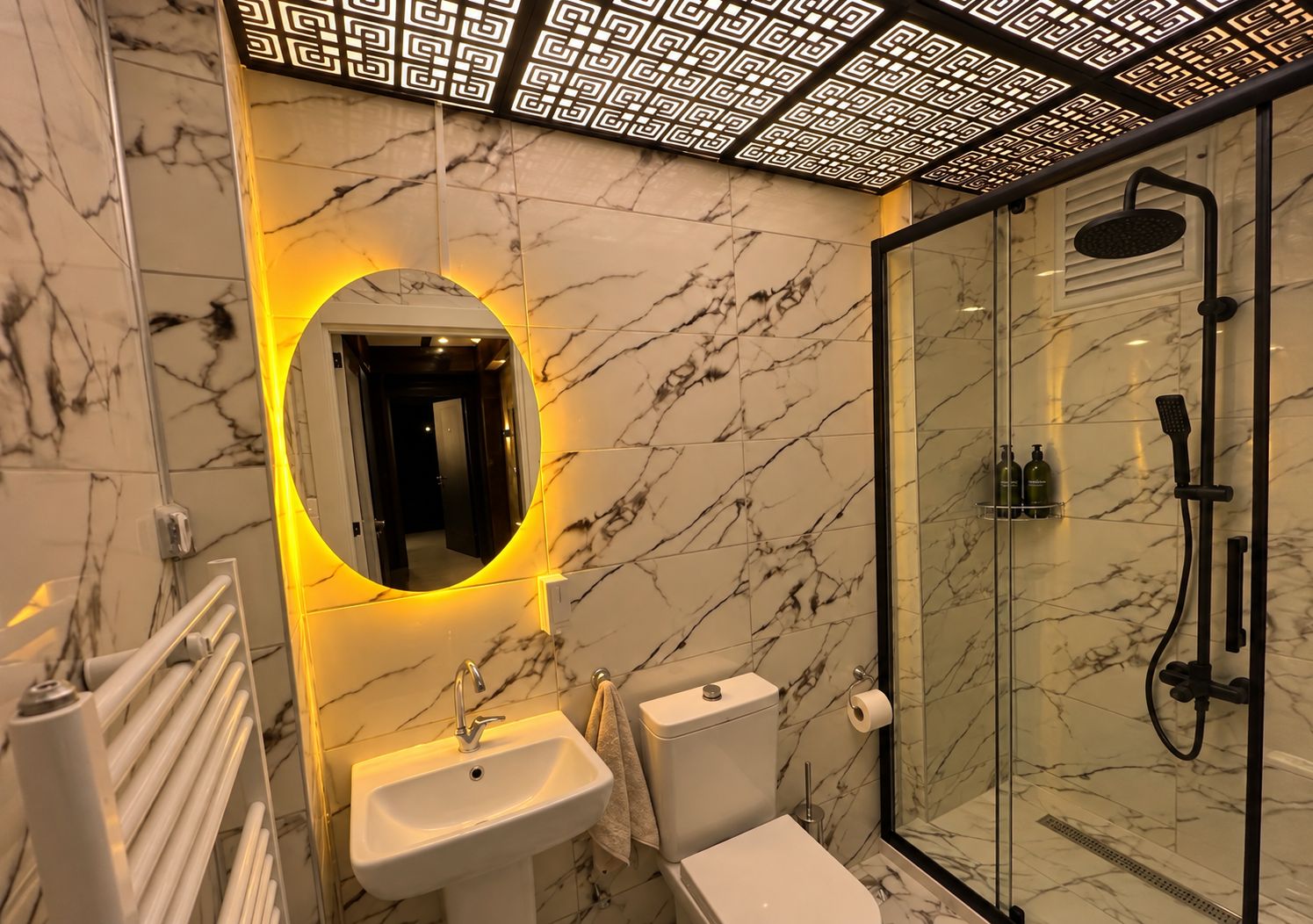 Une salle de bain avec un lavabo en marbre, des toilettes et une douche à parois de verre.