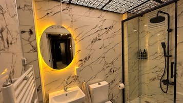 Une salle de bain avec un lavabo en marbre, des toilettes et une douche à parois de verre.