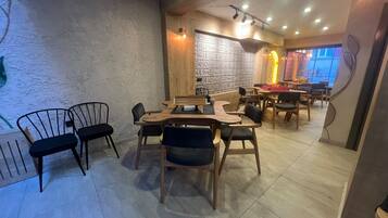 L’intérieur d’un restaurant avec des tables et des chaises en bois, un mur orné de motifs et un éclairage encastré au plafond.